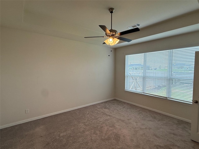 carpeted spare room with visible vents, baseboards, and ceiling fan