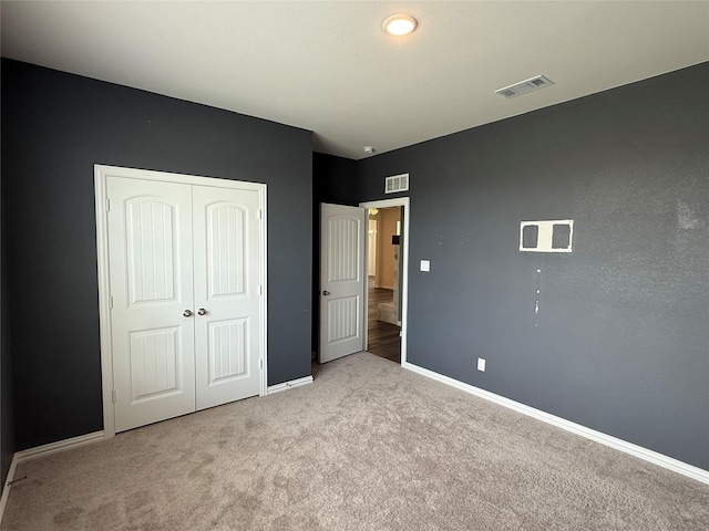 unfurnished bedroom with baseboards, a closet, visible vents, and carpet floors