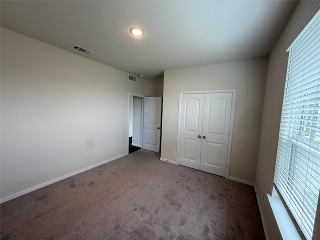 unfurnished bedroom featuring carpet flooring, a closet, visible vents, and baseboards