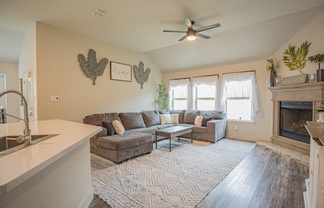 1025 N Churchill Dr, Fate, TX 75189 - living area with wood finished floors, ceiling fan, vaulted ceiling, a fireplace with raised hearth, and baseboards