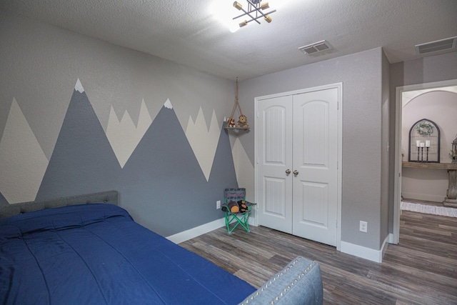 1025 N Churchill Dr, Fate, TX 75189 - bedroom with wood finished floors, a closet, baseboards, a textured ceiling, and arched walkways
