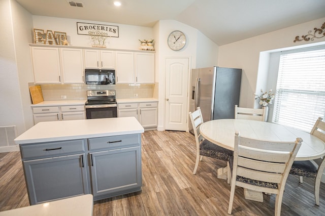 1025 N Churchill Dr, Fate, TX 75189 - kitchen featuring stainless steel appliances, gray cabinetry, wood finished floors, tasteful backsplash, and light countertops