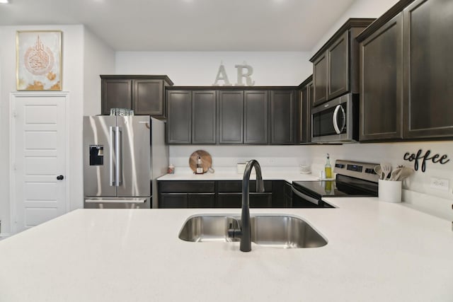 kitchen featuring light countertops, stainless steel appliances, a sink, and dark brown cabinetry