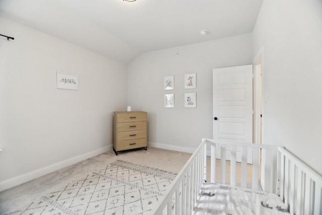 carpeted bedroom with a crib, baseboards, and lofted ceiling