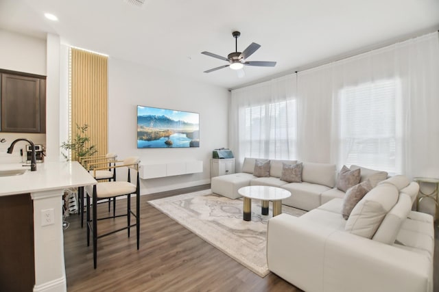 living room with baseboards, ceiling fan, and wood finished floors