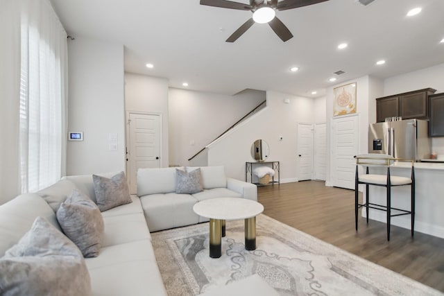 living room featuring wood finished floors, a ceiling fan, stairway, baseboards, and recessed lighting