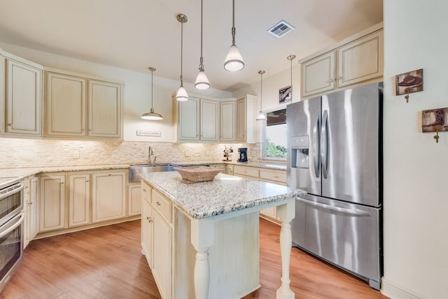 kitchen featuring appliances with stainless steel finishes, visible vents, cream cabinetry, and a sink