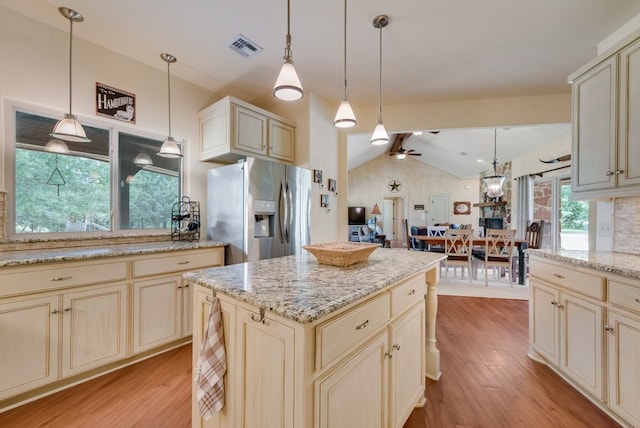 kitchen featuring stainless steel fridge with ice dispenser, vaulted ceiling, and cream cabinets