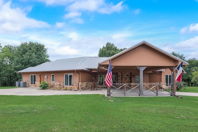 view of front of property with stone siding, stucco siding, a front yard, and metal roof