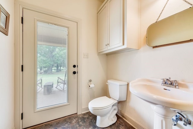 bathroom featuring toilet, baseboards, and a sink