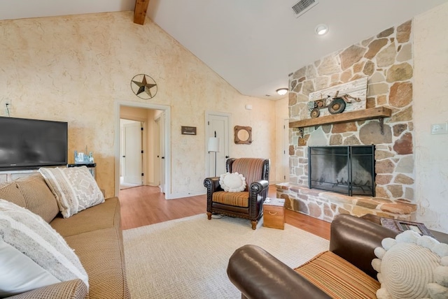 living area featuring visible vents, high vaulted ceiling, wood finished floors, a fireplace, and beam ceiling