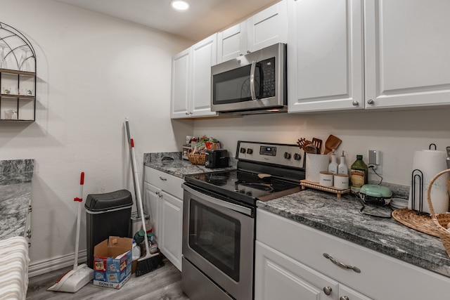 1100 Hillburn Dr, Dallas, TX 75217 - kitchen featuring dark stone countertops, appliances with stainless steel finishes, wood finished floors, and white cabinetry
