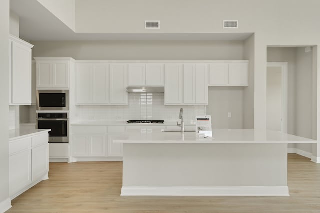 5614 Gaelic Dr, Celina, TX 75009 - kitchen with stainless steel appliances, backsplash, light wood-type flooring, and under cabinet range hood