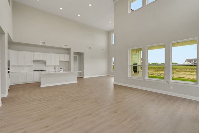 5614 Gaelic Dr, Celina, TX 75009 - unfurnished living room with a high ceiling, light wood-style flooring, and recessed lighting