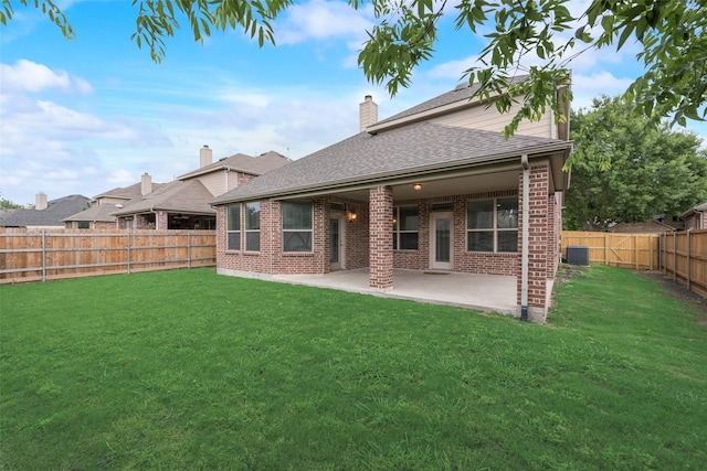 back of property with a yard, roof with shingles, a fenced backyard, and brick siding