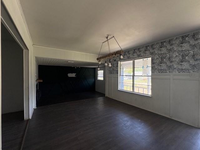 unfurnished dining area featuring a decorative wall, wainscoting, and dark wood-style floors