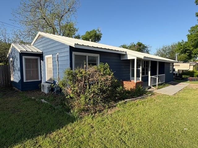 back of property featuring a yard and metal roof