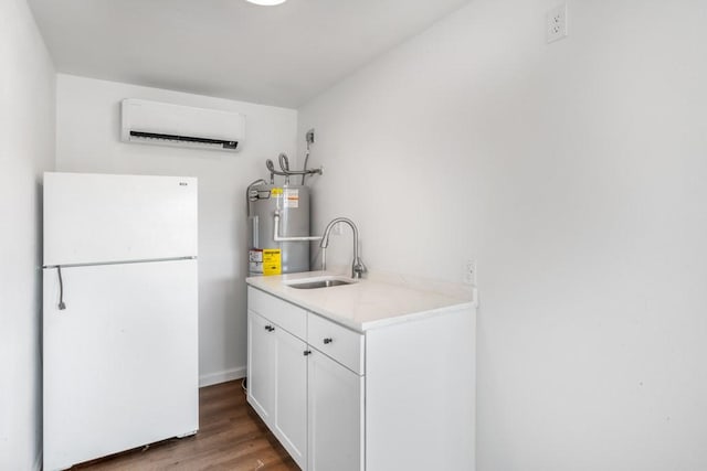 2349 Cooke St, Abilene, TX 79605 - kitchen with freestanding refrigerator, a sink, electric water heater, a wall unit AC, and wood finished floors