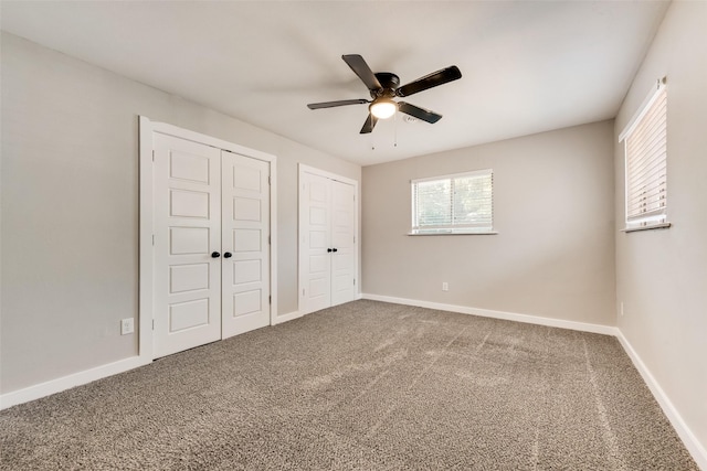 unfurnished bedroom featuring multiple closets, carpet flooring, and baseboards