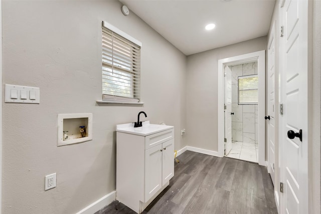 washroom featuring washer hookup, baseboards, dark wood-style flooring, and cabinet space