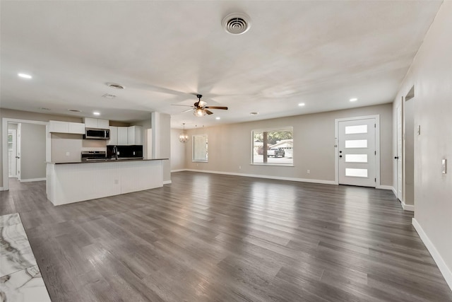 unfurnished living room featuring a ceiling fan, dark wood-type flooring, baseboards, recessed lighting, and a sink