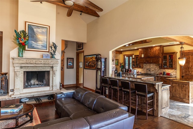 SQ13 Lake Cherokee, Henderson, TX 75652 - living room featuring beam ceiling, dark wood-style flooring, ceiling fan, arched walkways, and a fireplace with raised hearth