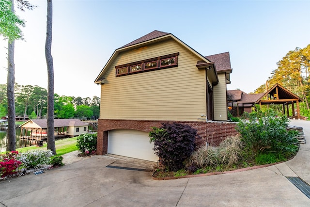 SQ13 Lake Cherokee, Henderson, TX 75652 - view of side of home featuring concrete driveway, an attached garage, a shingled roof, and brick siding