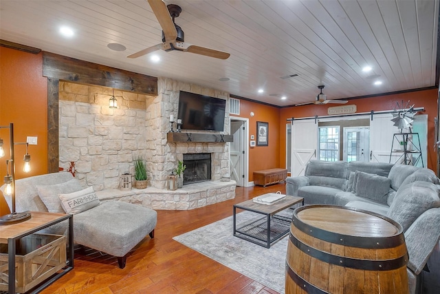 living room with wood ceiling, a fireplace, a barn door, ceiling fan, and hardwood / wood-style flooring