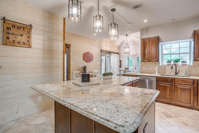 kitchen with a sink, decorative backsplash, stainless steel dishwasher, light stone countertops, and a kitchen island