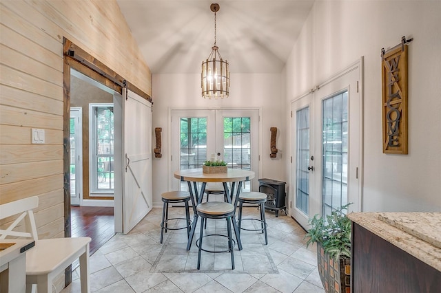 dining room with an inviting chandelier, french doors, a barn door, and vaulted ceiling