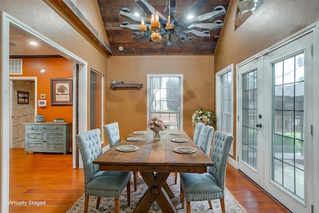 dining room with an inviting chandelier, high vaulted ceiling, beamed ceiling, and hardwood / wood-style flooring