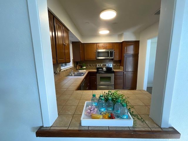 9434 Chimney Corner Ln, Dallas, TX 75243 - kitchen with a sink, tile patterned floors, tile countertops, appliances with stainless steel finishes, and tasteful backsplash