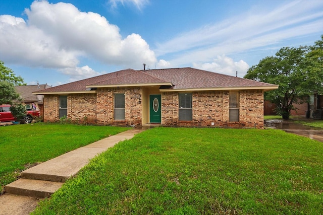ranch-style house with a shingled roof, brick siding, and a front yard