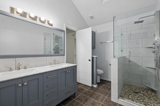 bathroom with a sink, lofted ceiling, a shower stall, and visible vents