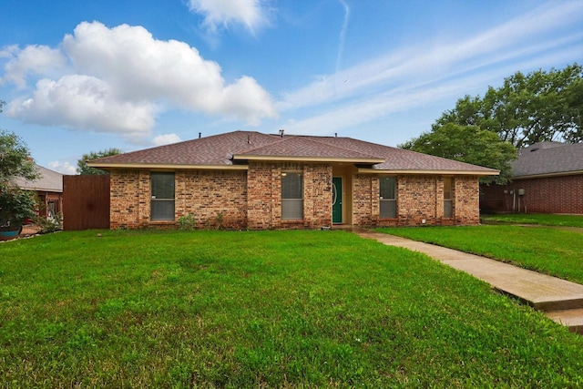 back of house with a yard, roof with shingles, and brick siding
