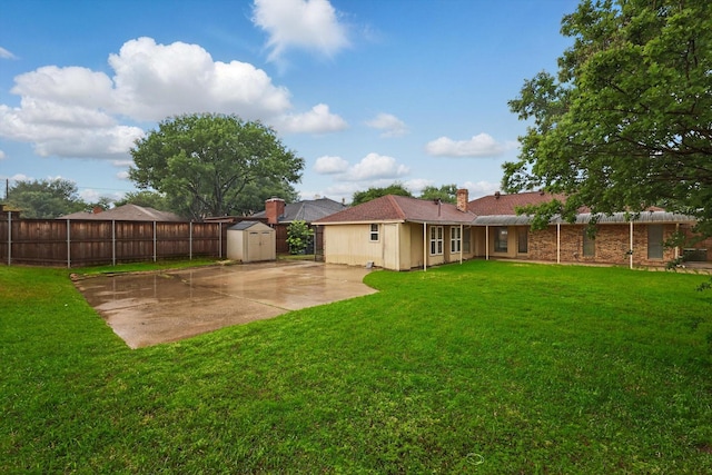 view of yard with an outbuilding, a shed, fence, and a patio