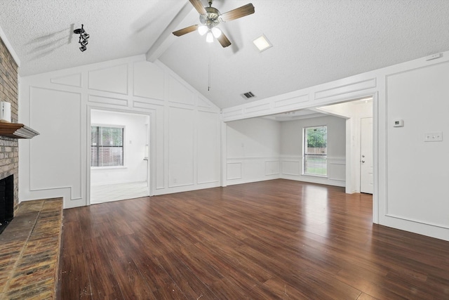 unfurnished living room with wood finished floors, a ceiling fan, a brick fireplace, a textured ceiling, and a decorative wall