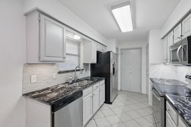 kitchen with light tile patterned flooring, a sink, dark stone counters, tasteful backsplash, and appliances with stainless steel finishes