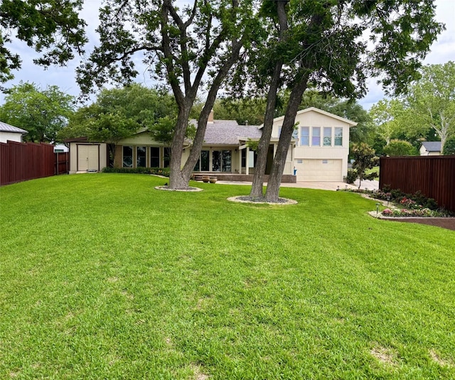 rear view of house with a lawn, a shed, a garage, and fence