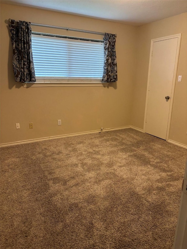 carpeted spare room with baseboards and plenty of natural light