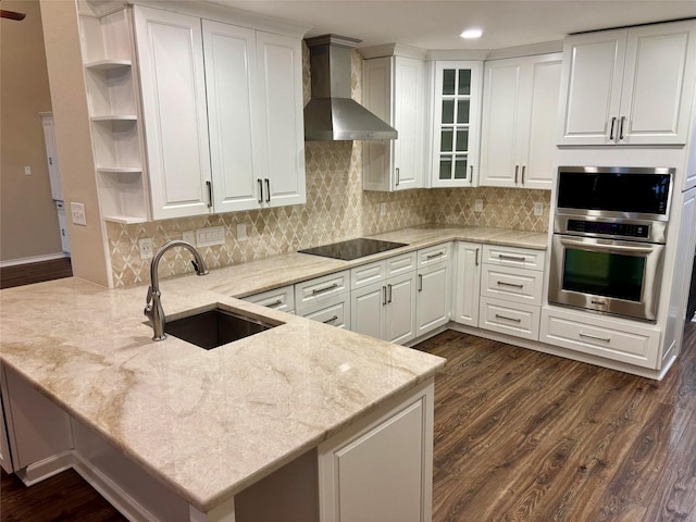 kitchen featuring stainless steel oven, a sink, a peninsula, open shelves, and wall chimney range hood