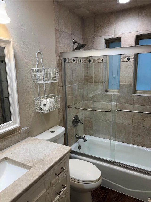 full bath with vanity, toilet, bath / shower combo with glass door, and wood finished floors