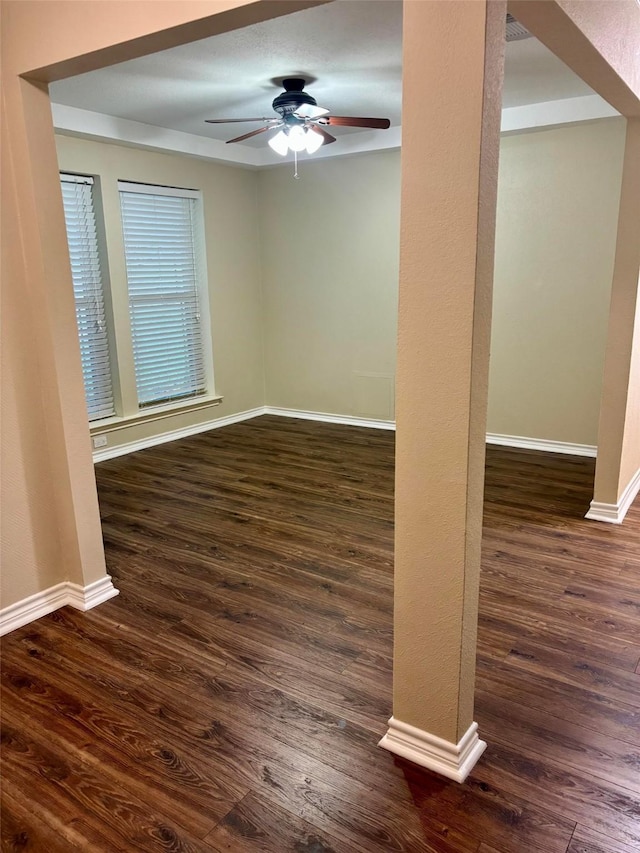 spare room featuring baseboards, ceiling fan, and dark wood-style floors