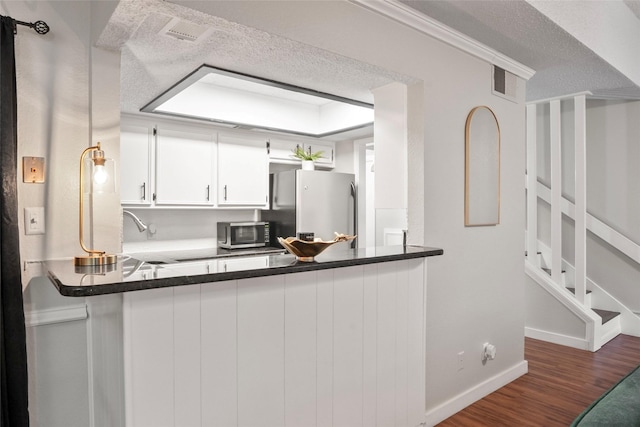 703 Trinidad Dr, Grand Prairie, TX 75052 - kitchen featuring stainless steel appliances, wood finished floors, a textured ceiling, a peninsula, and baseboards