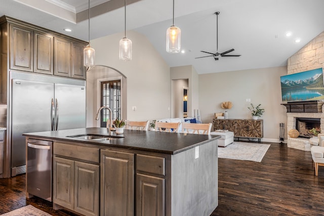 kitchen with a sink, stainless steel appliances, open floor plan, a ceiling fan, and arched walkways