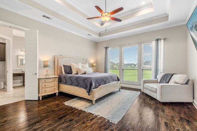 bedroom featuring a tray ceiling, crown molding, visible vents, and wood finished floors
