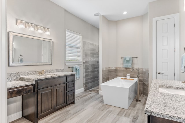 bathroom with a freestanding tub, two vanities, and a sink