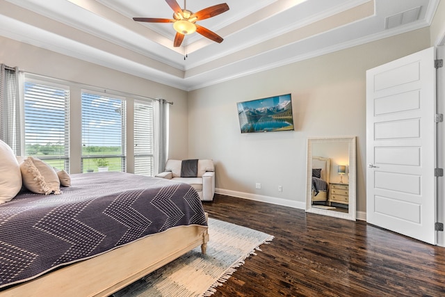 bedroom with a tray ceiling, ornamental molding, visible vents, and wood finished floors