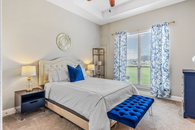 bedroom featuring baseboards, a raised ceiling, a ceiling fan, and carpet