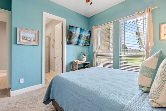 bedroom featuring ensuite bathroom, carpet, baseboards, and a ceiling fan